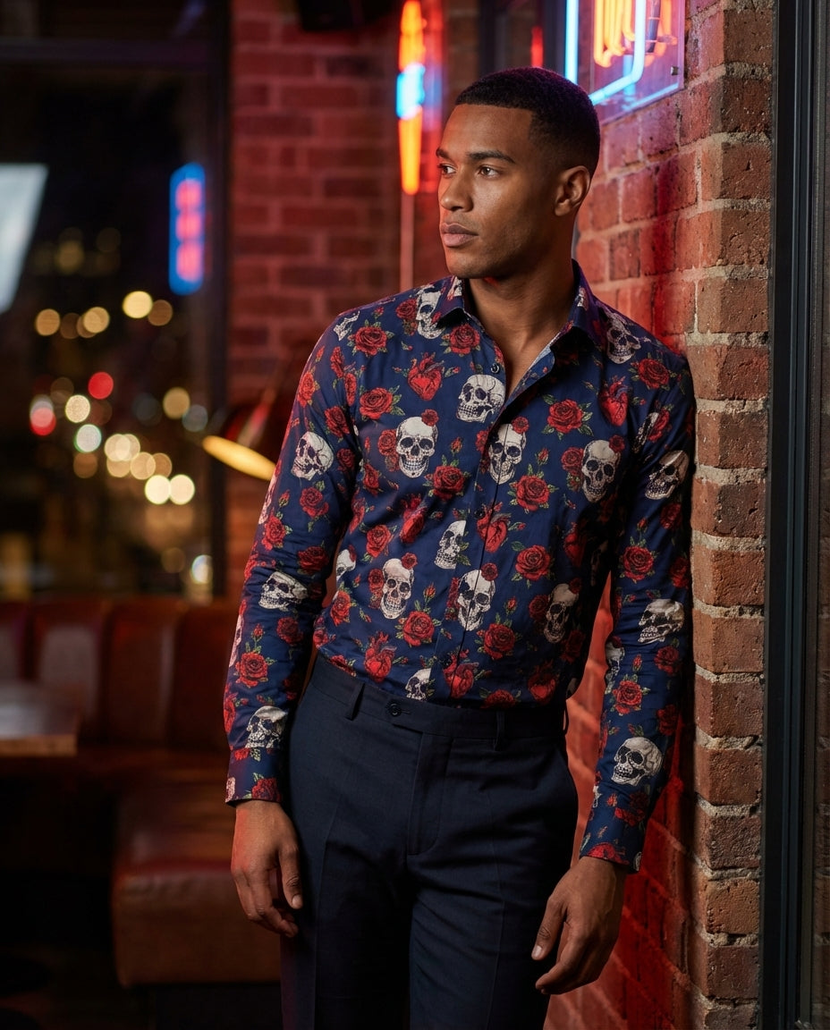 This bold, long-sleeved button-down shirt features an intricate all-over print of skulls, red roses, and hearts against a deep navy blue background. Crafted with a tailored fit and structured collar, it blends edgy rock-and-roll aesthetics with sophistica