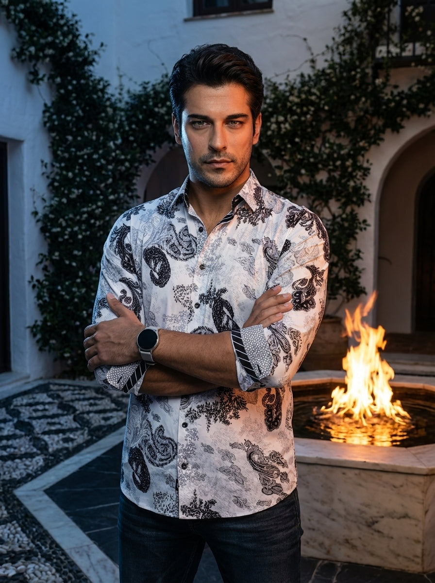 This sophisticated long-sleeve button-down shirt features an intricate black paisley and floral pattern set against a crisp white background. It includes unique contrasting cuff details and a tailored fit, making it an ideal choice for a modern, stylish l