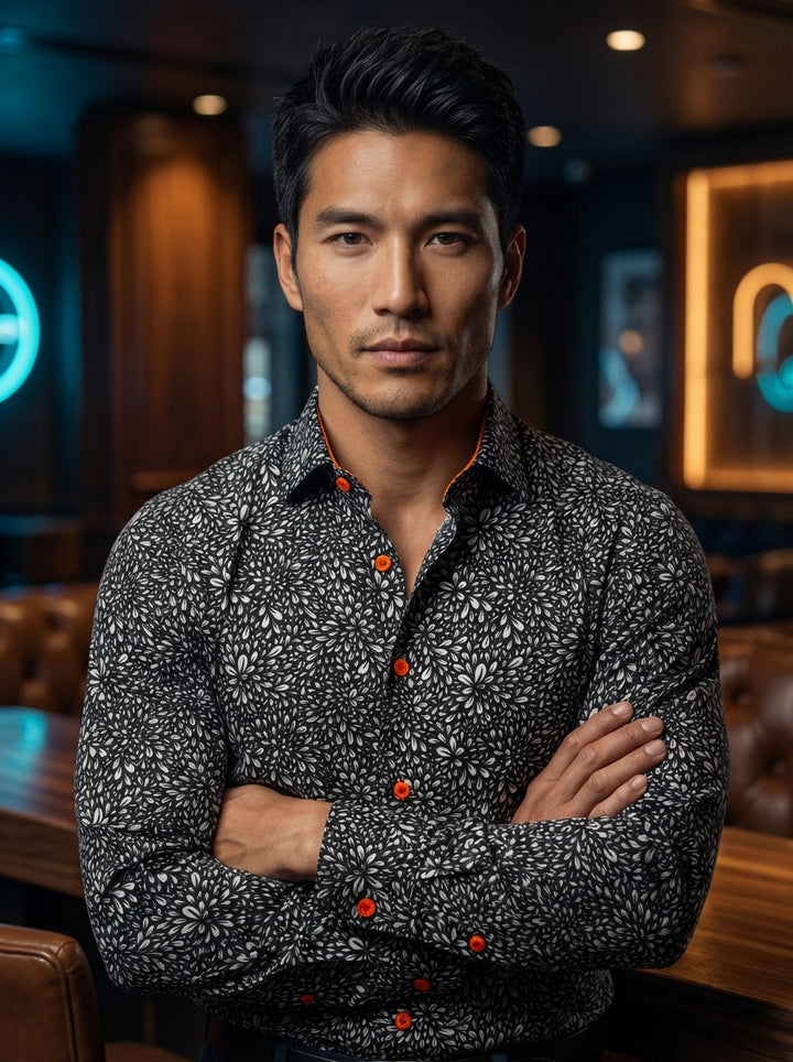 This Masutto long-sleeve button-down shirt features a striking monochromatic floral petal print set against a black ground. Vibrant orange buttons and interior collar piping provide a bold, energetic contrast, while the tailored fit ensures a sophisticate