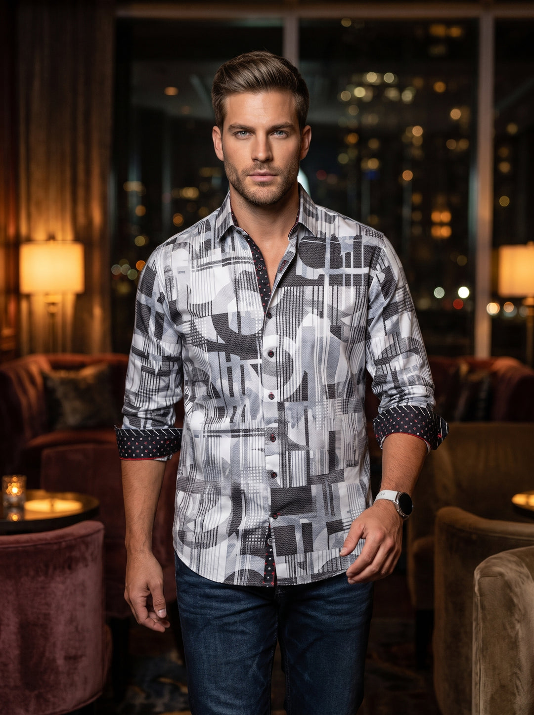 A sophisticated long-sleeve button-down shirt featuring a bold geometric abstract print in shades of grey, black, and white. The design includes contrasting red and black patterned inner cuffs and collar trim, paired with dark denim for a modern look.