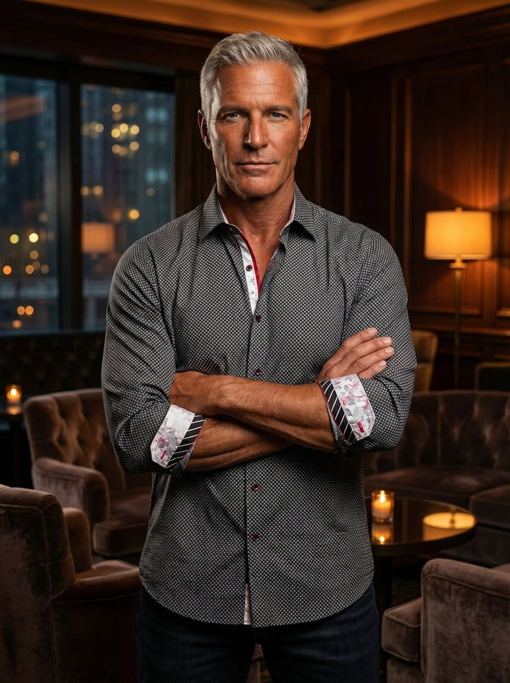This sophisticated men's button-down shirt features a charcoal and white micro-geometric pattern. It is elevated by contrast floral interior cuffs, a red-trimmed placket, and a classic spread collar, making it a versatile piece for stylish evening or prof