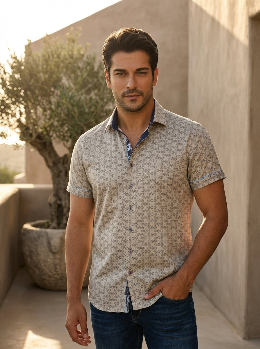 A sophisticated men's short-sleeve button-down shirt featuring a geometric tan and grey motif. The design includes a contrasting navy blue inner collar with whimsical patterned piping, finished with premium buttons and tailored rolled cuffs for a modern, 