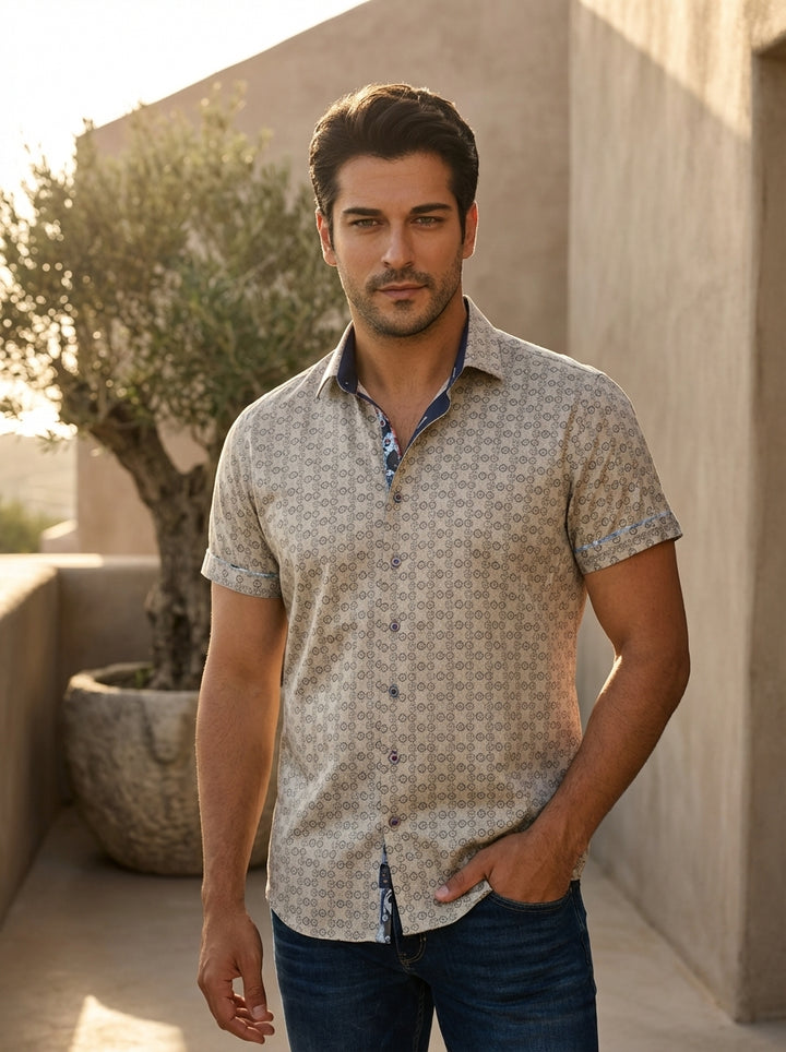 A sophisticated men's short-sleeve button-down shirt featuring a geometric tan and grey motif. The design includes a contrasting navy blue inner collar with whimsical patterned piping, finished with premium buttons and tailored rolled cuffs for a modern, 