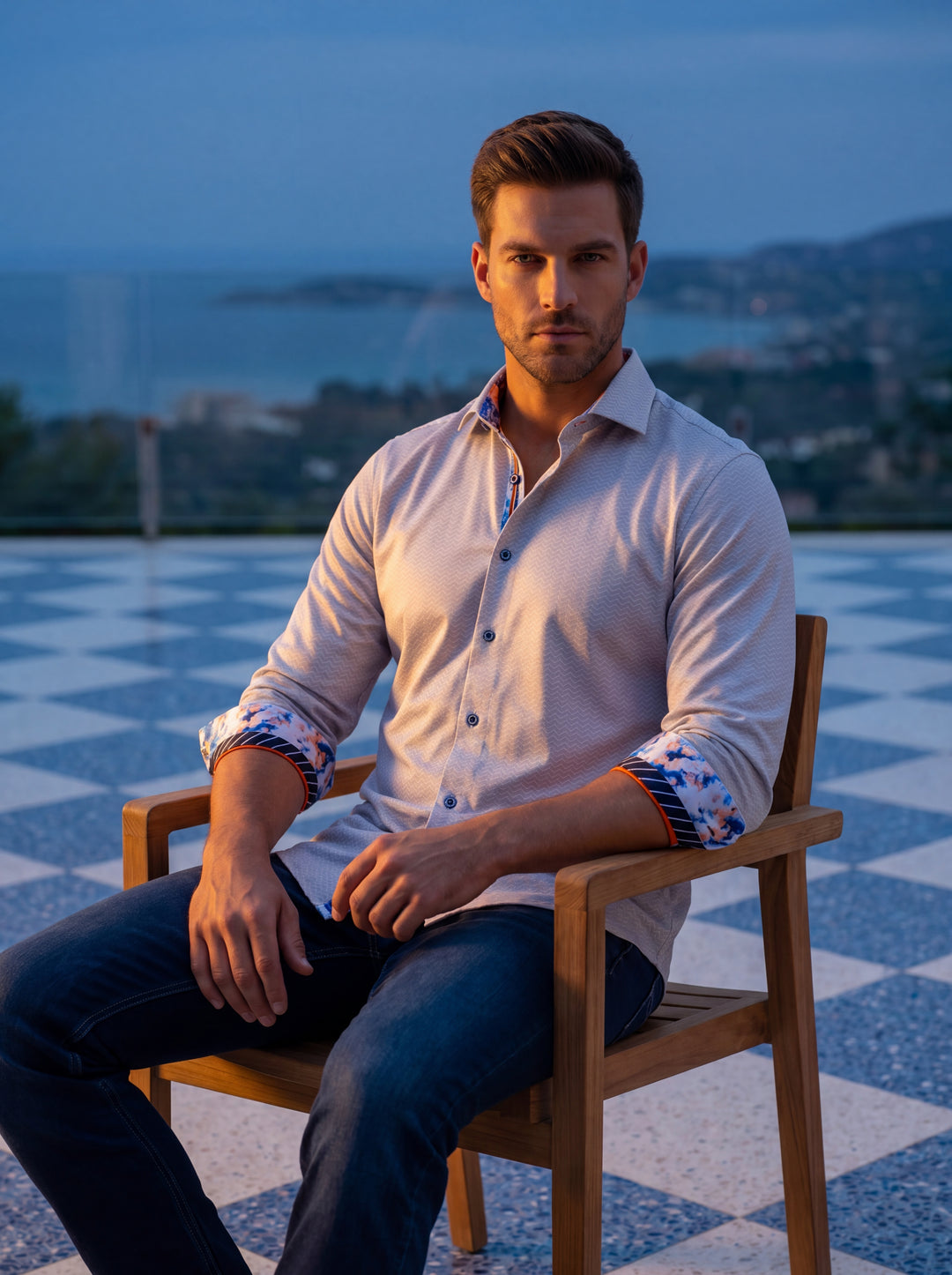 A sophisticated light grey button-down shirt featuring a subtle wavy texture. The inner collar and rolled cuffs reveal vibrant orange, blue, and white floral patterns with striped piping. Designed with a tailored fit, it blends classic style with modern a