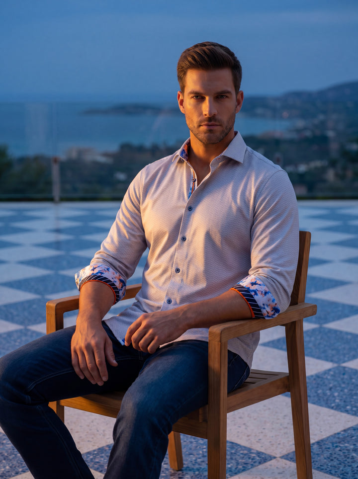 A sophisticated light grey button-down shirt featuring a subtle wavy texture. The inner collar and rolled cuffs reveal vibrant orange, blue, and white floral patterns with striped piping. Designed with a tailored fit, it blends classic style with modern a