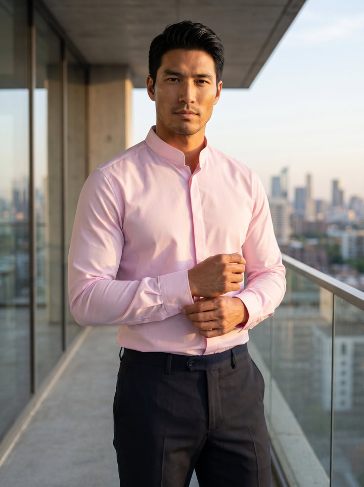 A light pink long-sleeved dress shirt featuring a modern band collar and hidden placket design. Made from smooth cotton fabric, it includes adjustable button cuffs and a tailored fit for a sleek, contemporary silhouette.