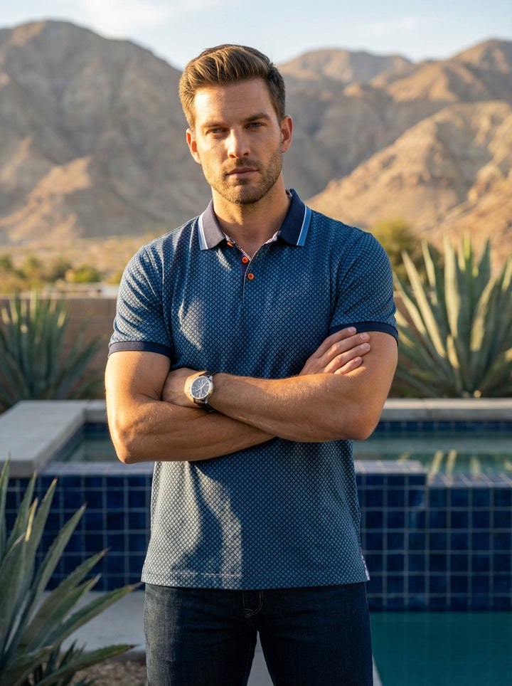 This sophisticated blue polo shirt features a detailed geometric diamond print and a contrasting tipped collar. Crafted for comfort, it includes unique orange button accents and a tailored fit, making it a versatile staple for the modern man's stylish war