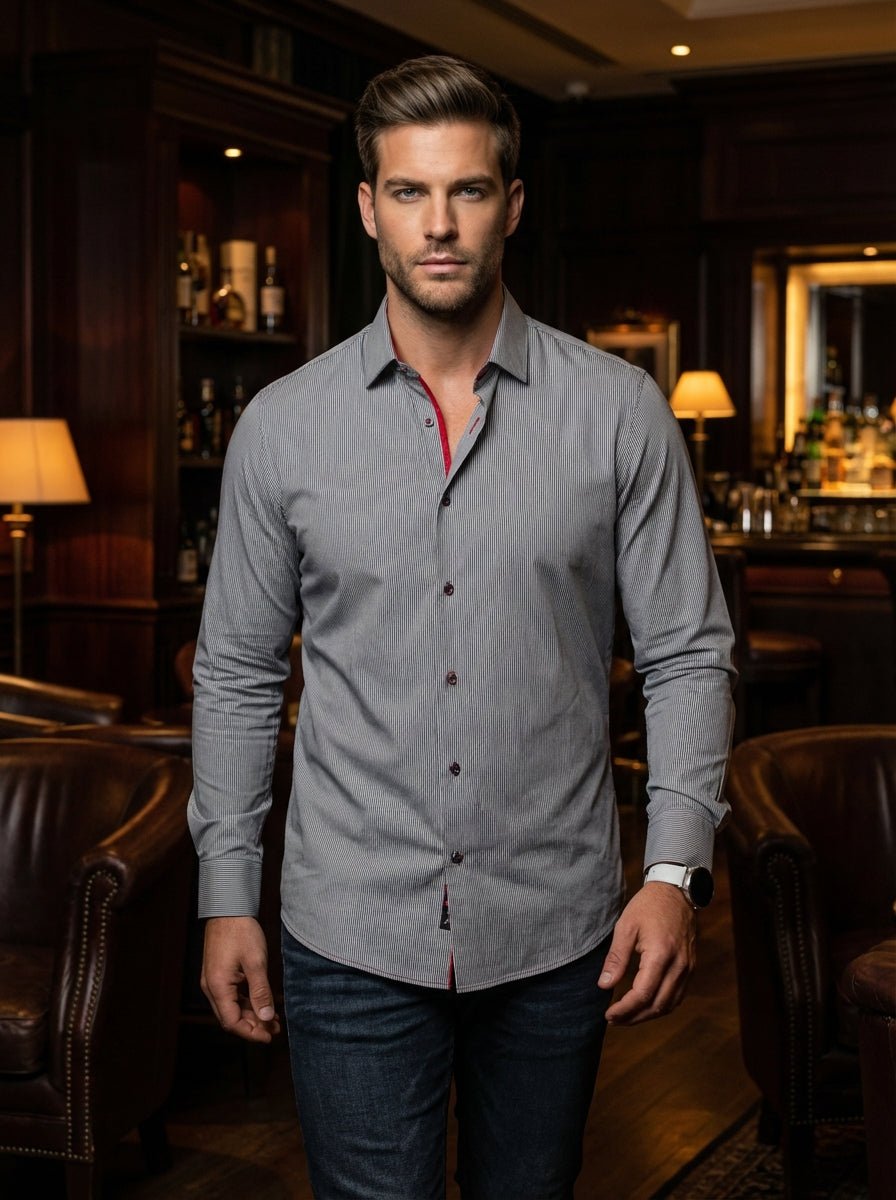 This sophisticated men's button-down shirt features a fine grey and white vertical stripe pattern. It is accented with bold red piping inside the collar for a modern touch. Crafted for a tailored fit, it pairs perfectly with dark denim.