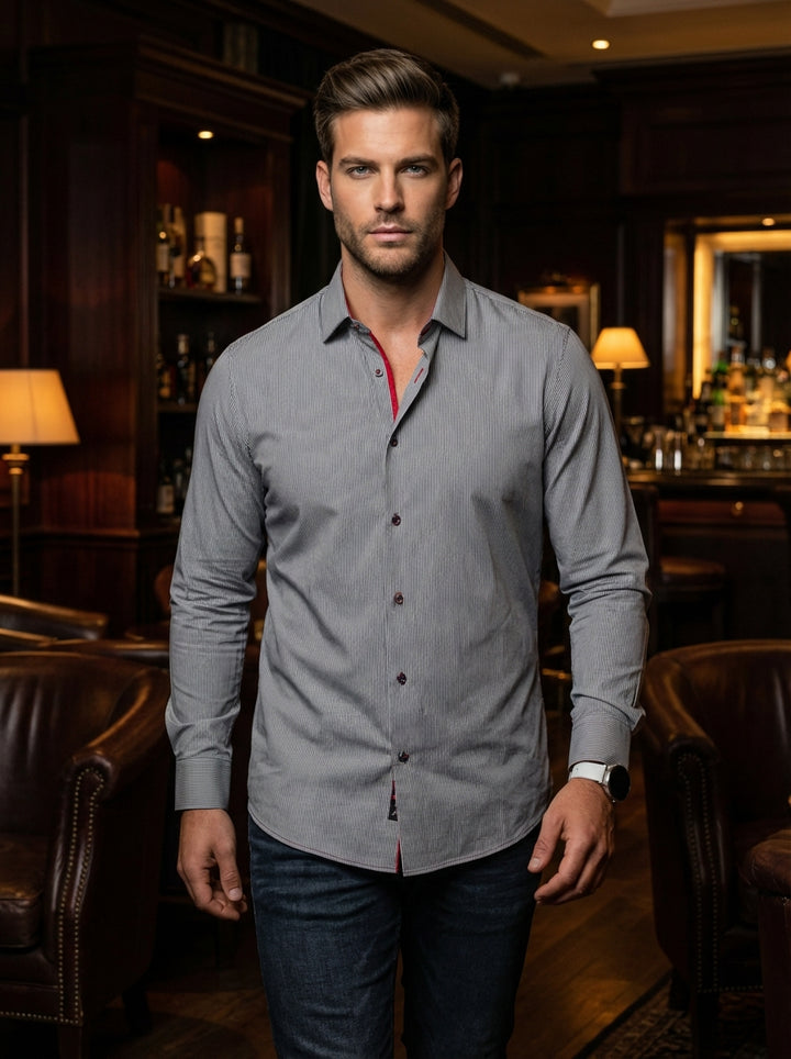 This sophisticated men's button-down shirt features a fine grey and white vertical stripe pattern. It is accented with bold red piping inside the collar for a modern touch. Crafted for a tailored fit, it pairs perfectly with dark denim.
