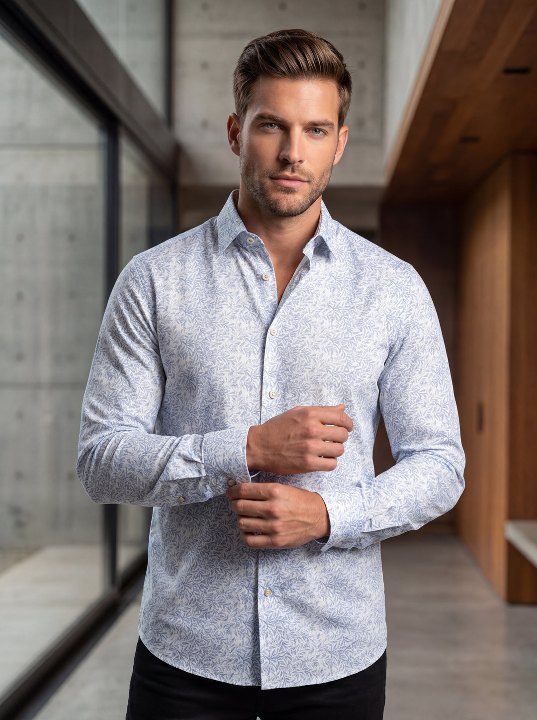 This men's long-sleeve button-down shirt features an intricate light blue botanical leaf pattern on a crisp white background. It offers a modern tailored fit with a classic collar and pearlescent buttons, perfect for elevating casual looks with sophistica