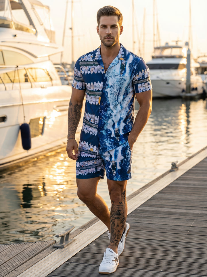 This bold two-piece matching set features a vibrant blue nautical print showcasing stylized yachts and crashing ocean waves. The short-sleeve button-down shirt and coordinated shorts offer a relaxed fit, perfect for making a stylish statement during summe