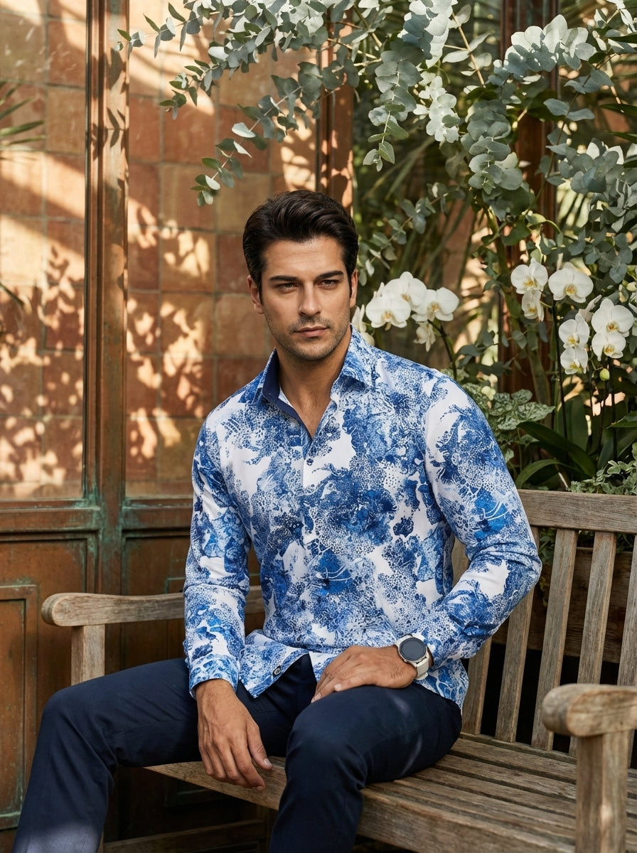 This men's long-sleeve button-down shirt features an intricate blue and white floral-toile pattern. Crafted with a tailored fit and contrasting dark blue collar lining, it offers a sophisticated yet bold aesthetic perfect for making a statement in contemp