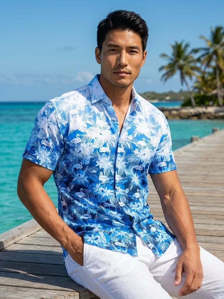 This men's short-sleeve button-down shirt features a vibrant tropical print with flamingos and palm leaves. The design utilizes a striking blue-to-white vertical ombre effect. Crafted from lightweight fabric, it offers a regular fit with a classic pointed