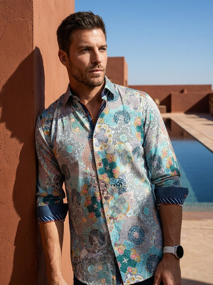 This men's long-sleeve button-down shirt features an intricate, multi-colored kaleidoscopic paisley and floral pattern. The vibrant design includes teal, orange, and navy accents, complemented by contrasting patterned inner cuffs and collar trim for a sop
