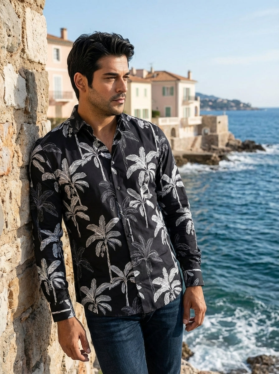 This men's long-sleeve button-down shirt features a sophisticated black base with a bold, white tropical palm tree print. Crafted from a smooth fabric, it offers a tailored fit that pairs effortlessly with dark denim for a modern, stylish look.