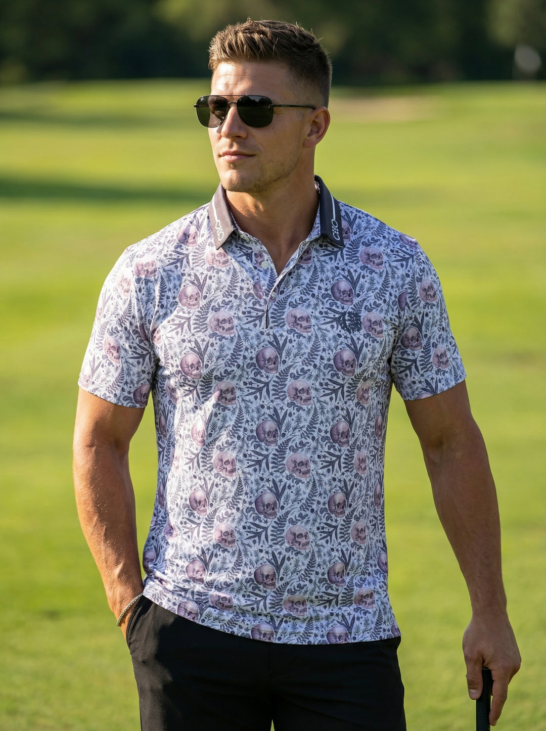 This short-sleeved performance polo features a unique all-over print of purple skulls intertwined with delicate botanical ferns. The garment is finished with a contrasting charcoal grey collar detailed with branded text, offering a bold yet sophisticated 