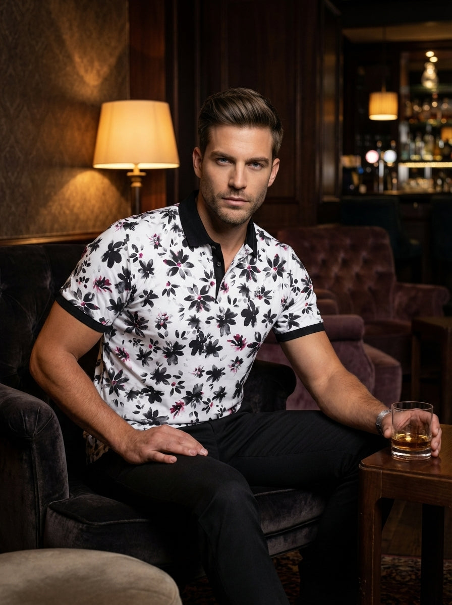 This stylish men's short-sleeve polo features a vibrant white base with a charcoal floral print and pink accents. It is designed with a contrasting black collar and ribbed cuffs, offering a modern, tailored fit for a sophisticated, casual look.
