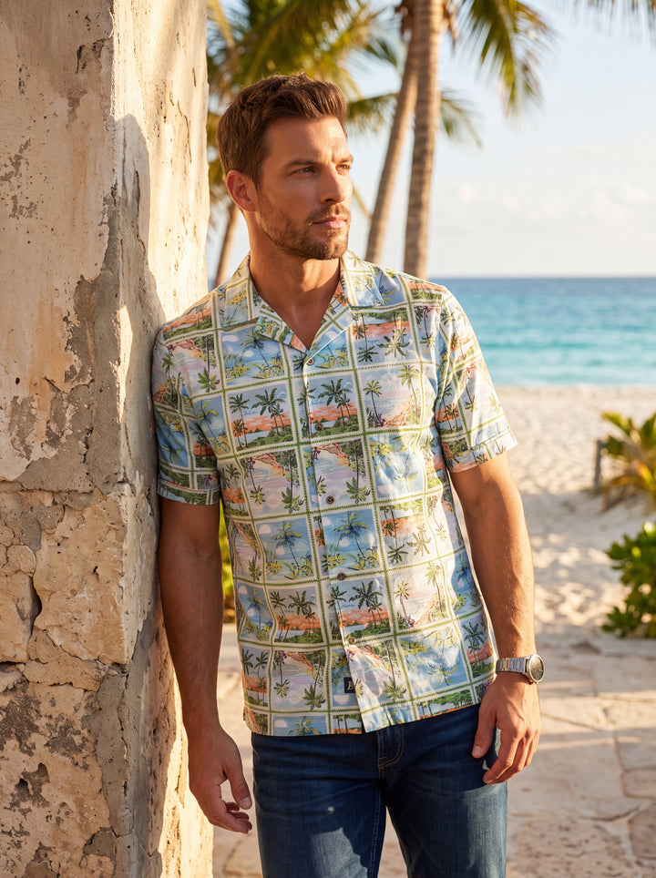 This men's short-sleeve button-down shirt features a vibrant tropical postcard print in a grid layout. The lightweight fabric showcases serene beach scenes with palm trees and sun-drenched landscapes, complete with a relaxed camp collar and paired with da