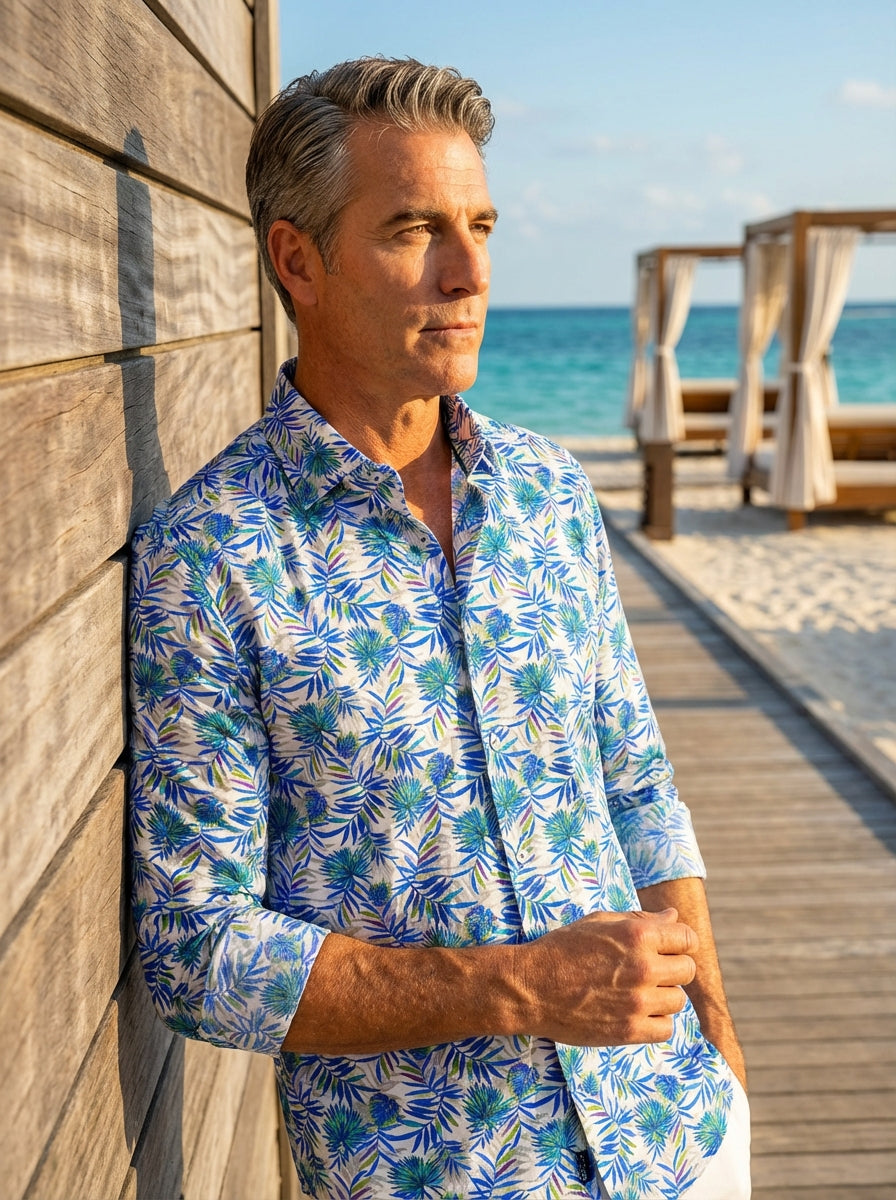 This premium Masutto button-down shirt features a vibrant tropical palm leaf pattern in shades of blue and green over a crisp white base. The tailored design includes a refined spread collar, button cuffs, and high-quality construction for vacation elegan