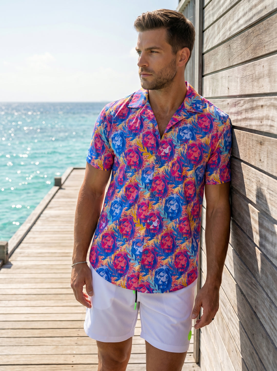This vibrant short-sleeve button-down shirt features a bold, artistic all-over print of lion portraits in saturated shades of electric blue, hot pink, and sunny yellow. Crafted with a classic camp collar, it offers a modern, slim-fit silhouette for summer