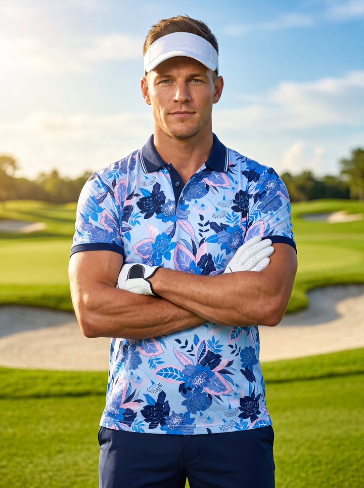 This vibrant light blue polo shirt features an intricate all-over floral print in shades of navy, azure, and soft pink. It is designed with a classic navy ribbed collar and matching sleeve cuffs, offering a refined yet playful tropical aesthetic.