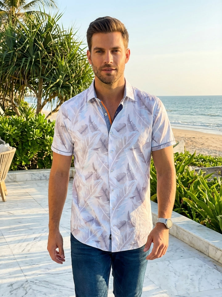 This stylish men's short-sleeve button-down shirt features a sophisticated white and pale blue palm leaf pattern. It is designed with a modern tailored fit, contrast inner collar detailing, and subtle orange accents that provide a pop of summer color.