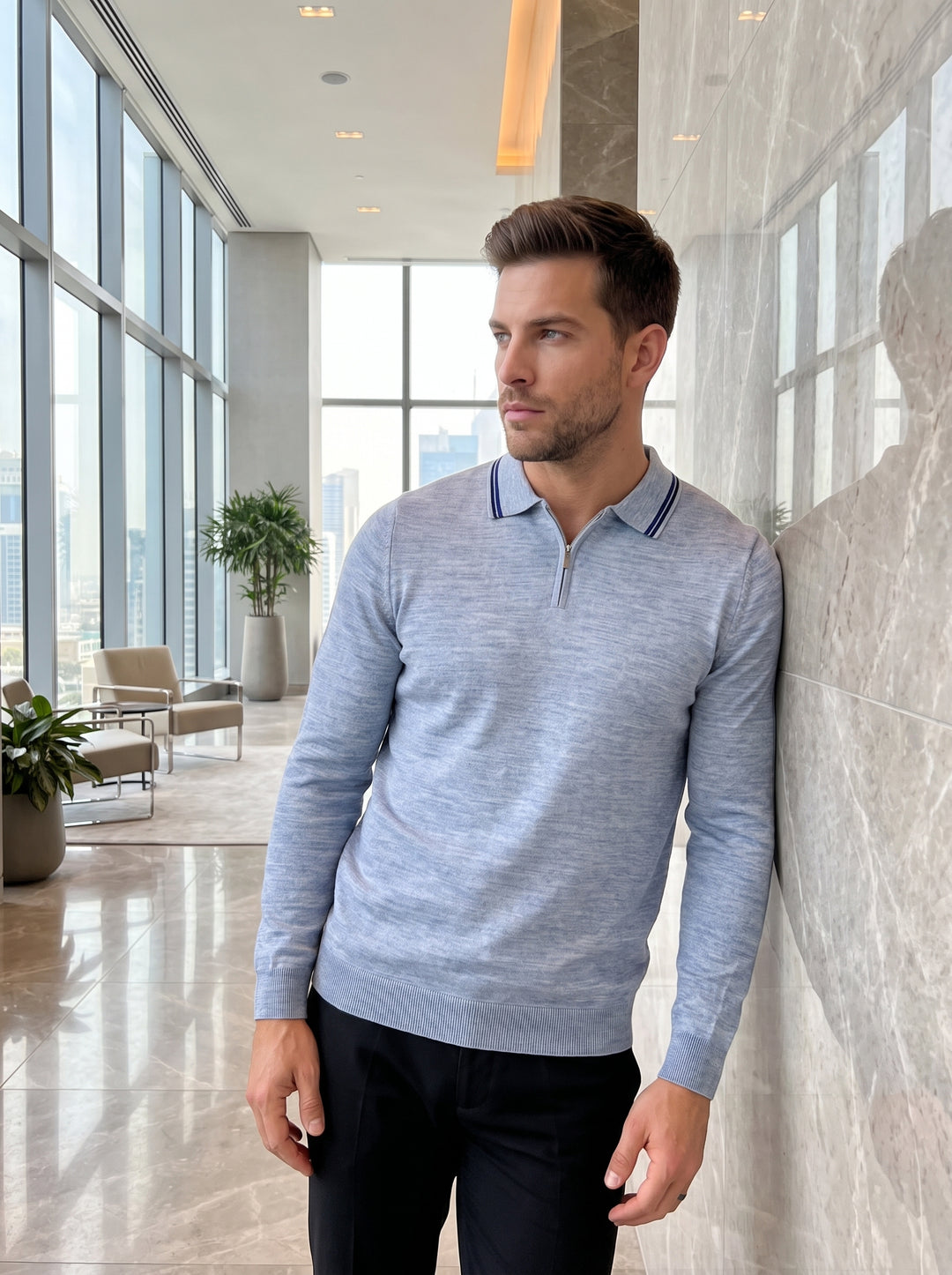 This light blue long-sleeve knit polo features a refined quarter-zip neckline and a classic collar accented with navy tipping. Crafted from a fine-gauge marled fabric, it offers a tailored fit with ribbed cuffs and hem for a polished, sophisticated look.