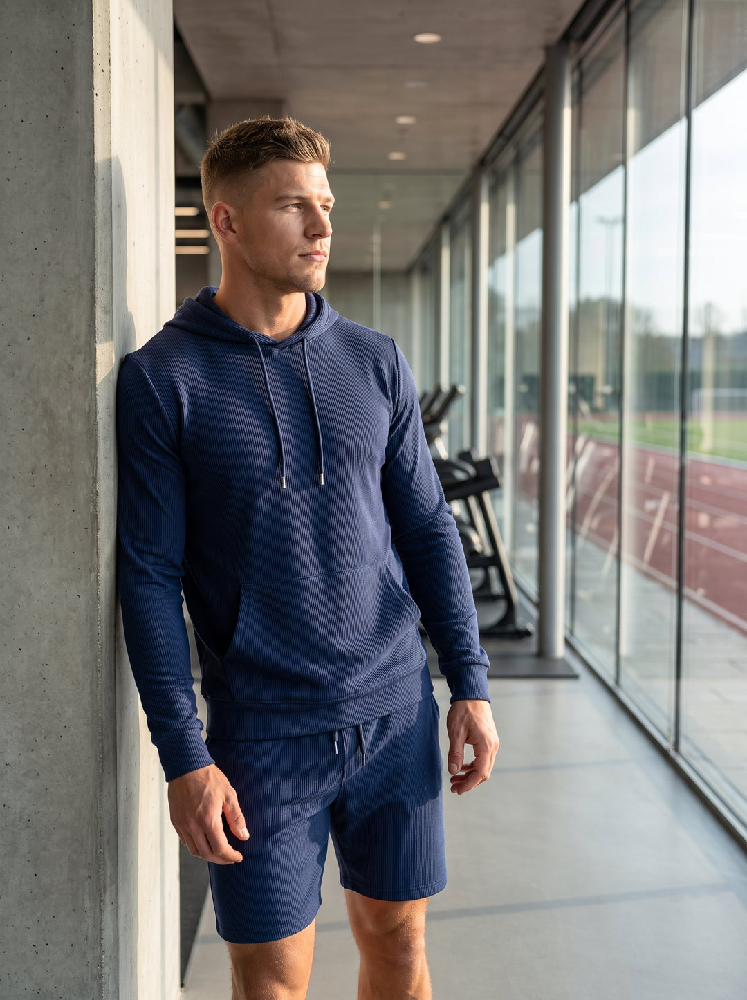This premium navy performance set features a long-sleeved textured hoodie with a spacious kangaroo pocket and matching technical shorts. Crafted from a breathable ribbed fabric, it offers a streamlined fit designed for both comfort and high-intensity athl