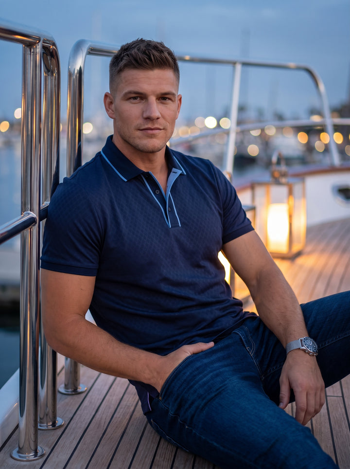 This navy short-sleeved polo shirt features a subtle jacquard diamond texture and a contrasting light blue trim on the collar and placket. Crafted for a slim fit, it offers a refined take on a classic silhouette with premium detailing.