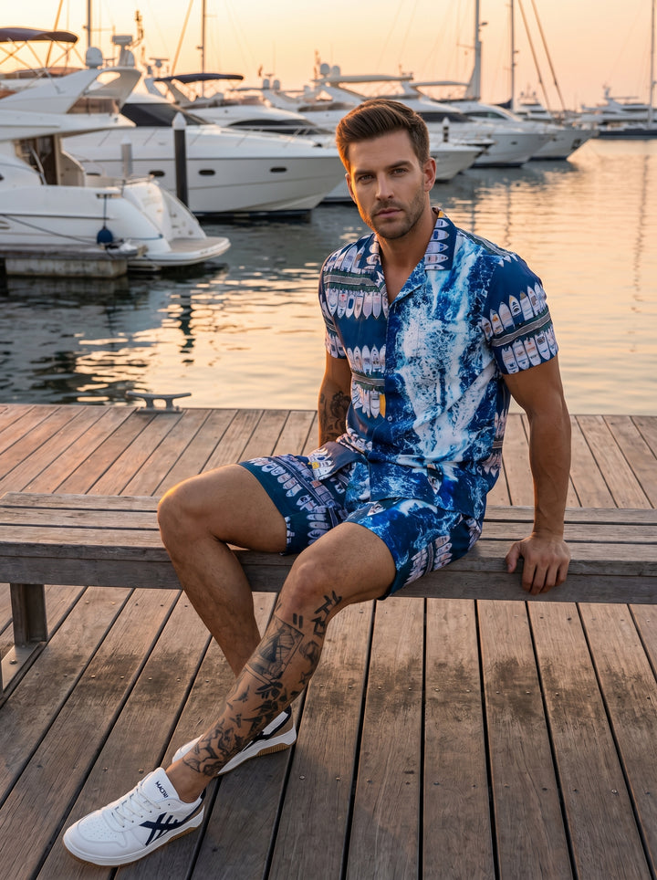 This bold two-piece matching set features a vibrant blue nautical print showcasing stylized yachts and crashing ocean waves. The short-sleeve button-down shirt and coordinated shorts offer a relaxed fit, perfect for making a stylish statement during summe