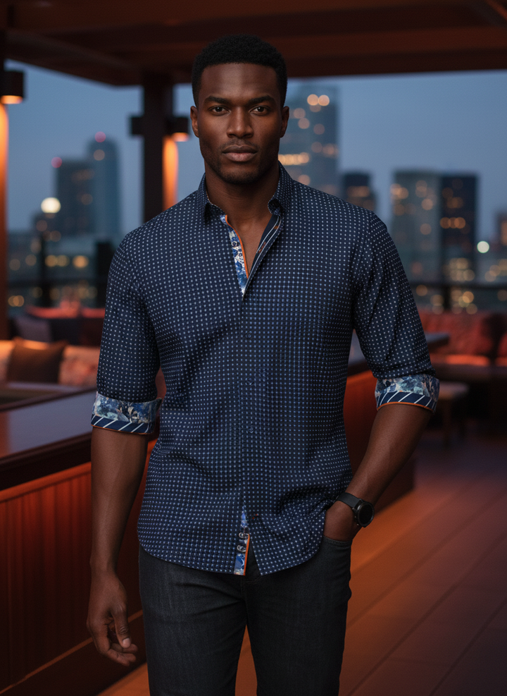 This navy button-down features a subtle grid pattern, elevated by vibrant orange piping and multi-patterned floral and striped inner cuffs. Tailored for a modern fit, it blends classic craftsmanship with contemporary, eclectic details for a standout look.